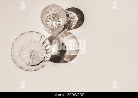 Summer decorative still life scene. Sparkling glasses of water, cocktails with long harsh shadows in sunlight. Beige table background . Flat lay, top Stock Photo