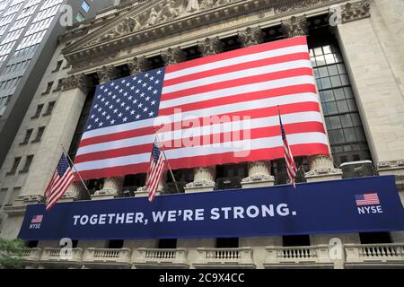 Exterior of the New York Stock Exchange with Together We’re Strong banner hanging during the coronavirus pandemic.  The NYSE partially reopened its trading room floor May 26, which was closed on March 23rd due to the COVID-19 pandemic, the first time operating with it closed in 228 years. Lower Manhattan, Financial District, New York City, USA May 2020 Stock Photo