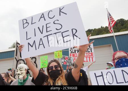 Zinc, Arkansas, USA. 2nd Aug, 2020. Aug. 2, 2020: Protesters hold up signs along Zinc Road which leads to the compound of the KKK. A variety of groups including Ozarks Hate Watch and Bridge the Gap NWA are marching on Zinc, AR, in a historic march (never before has Zinc had a march of Black groups). Zinc is home of Thomas Robb, who is the grandwizard of the KKK. Credit: Leslie Spurlock/ZUMA Wire/Alamy Live News Stock Photo