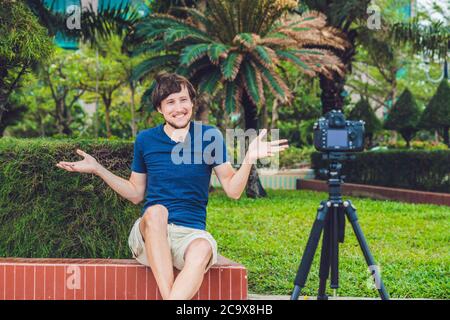 Young man blogger records video in front of the camera in the park Stock Photo