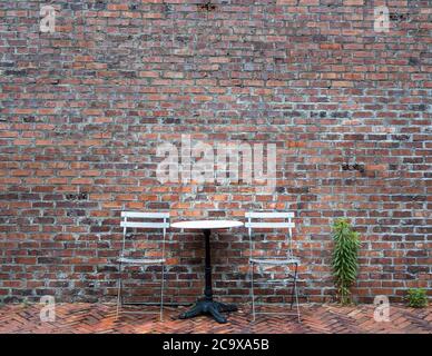 Two chairs and one table and small green tree in the background of brick wall. Coffee factory in Gangneung, Gangwon, South Korea. Roastery cafe. Stock Photo