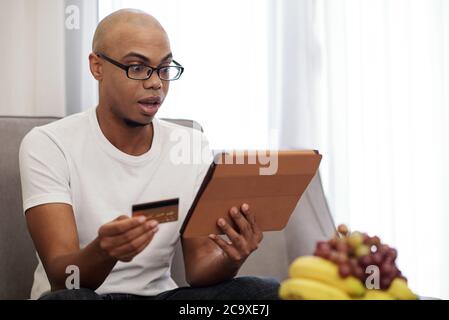 Black man shocked with high price of service he was going to pay for online Stock Photo