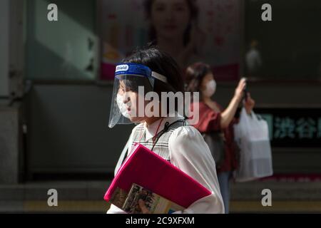 A woman wearing a face shield as a preventive measure walks on the street amid coronavirus crisis. The two-month long state of emergency declared by the Japanese government in response to the COVID-19 pandemic ended on June 1st. Despite Japan appearing to have avoided the high infection and mortality rates of some countries during the first wave of the crisis, many areas in Tokyo and across the country have seen businesses shuttered and closed, the cancelling of the 2020 Tokyo Olympics and increasing numbers of infections as people went back to more normal life after the shutdown. A second wav Stock Photo