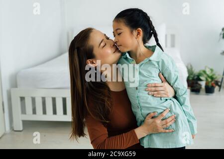 Affectionate Asian mother cuddling cute girl Stock Photo