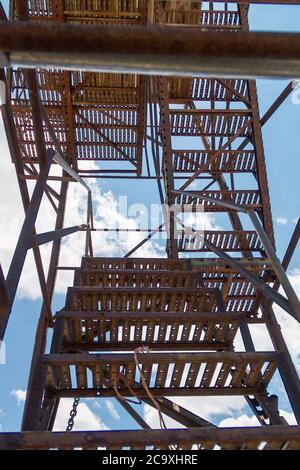 old rusty metal ladder in a blue sky with clouds Stock Photo