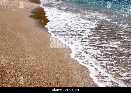 Sandy beach, soft waves rolling on the shore, reflections on the sea water, beach  background empty early in the morning. Stock Photo