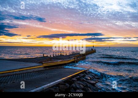 Beautiful glowing sunset over ocean and small boat jetty in Melbourne, Australia Stock Photo