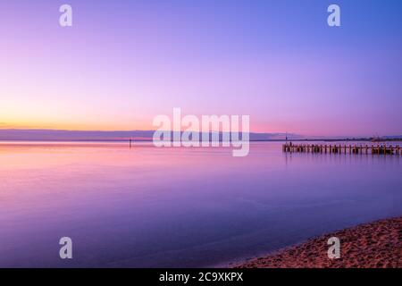 Amazing purple sunset over silky smooth water and boat jetty in Melbourne, Australia Stock Photo