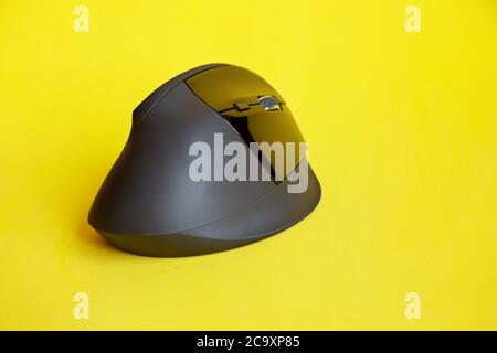 View of a black wireless mouse on yellow background,  with copy space Stock Photo