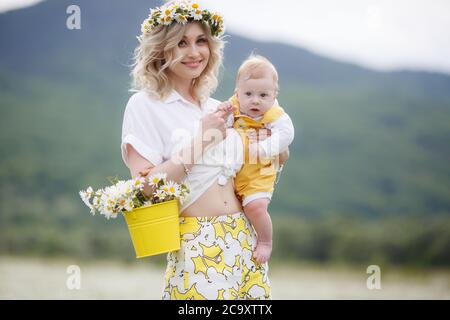 happy woman with little baby boy in camomilles. blooming white field. family in flowers. mother and son Stock Photo