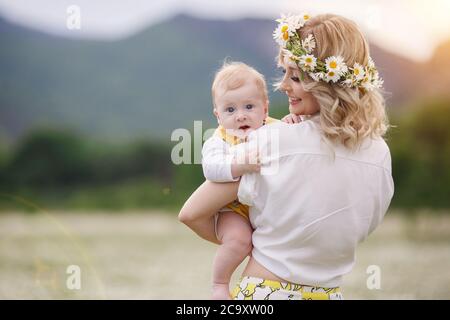 happy woman with little baby boy in camomilles. blooming white field. family in flowers. mother and son Stock Photo