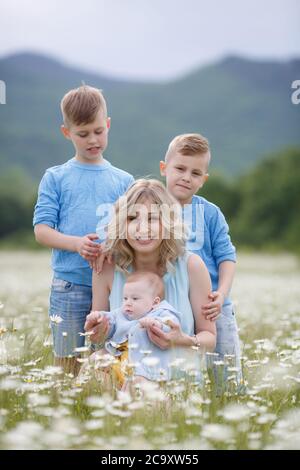 happy family in camomile field. woman with three children boys in camomiles outdoors Stock Photo