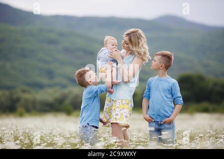 happy family in camomile field. woman with three children boys in camomiles outdoors Stock Photo