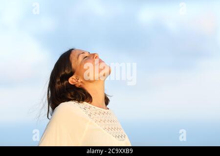 Relaxed adult woman breathing fresh air outdoors on the beach at summer Stock Photo