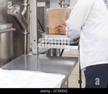 A male worker in production weighs and packs sweet products. Confectionery packaging concept, copy space for text, business Stock Photo