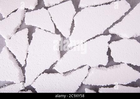 Pieces of white expanded polystyrene close-up on a gray background, flat layout Stock Photo