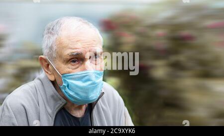 old man in a medical mask. old man wears a mask outdoors to avoid getting infected with the Corvette-19 virus. Prevention of viral diseases in the Stock Photo