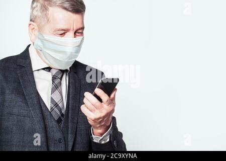 Senior man in medical protective face mask using smart phone isolated on white Stock Photo