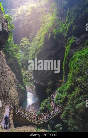 Wulong, China - August 2019 : Tourists walking on a wooden artificial cliff attached walkway path going through the gorge and the landscape of Wulong Stock Photo