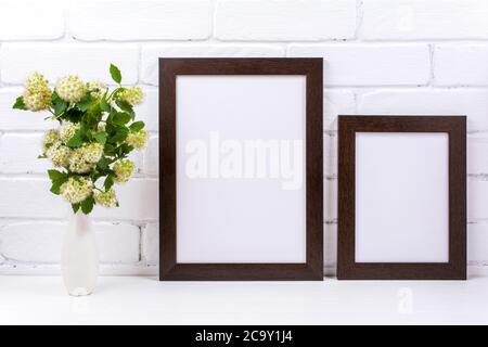 Two black brown frames mockup with white spirea branch in the vase. Empty poster frame mock up for presentation design. Template framing for modern ar Stock Photo
