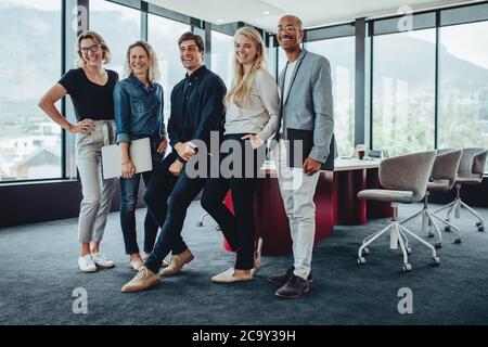 Diverse group of business people standing together in office boardroom. Group of professionals after a meeting in office. Stock Photo