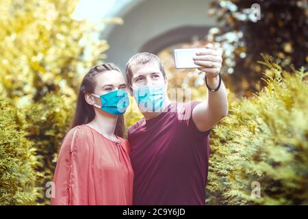 Young people with protective face masks taking selfie in city Stock Photo
