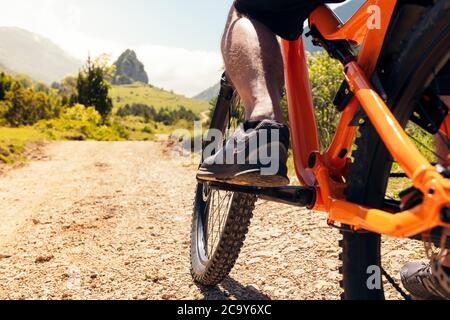 close up of the wheels of a mountain bike with cyclist on a dirt path, concept of sport and healthy lifestyle in nature, copy space for text Stock Photo