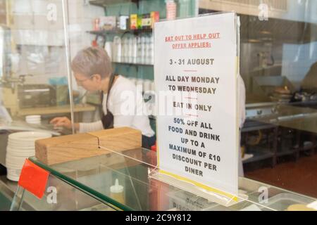 Signage for the 'Eat Out to Help Out' scheme, at the Regency Cafe, in London, one of the participating restaurants where diners will be able to enjoy half-price meals, starting on Monday as the Government kick-starts its August scheme aimed at boosting restaurant and pub trade following the lockdown. Stock Photo