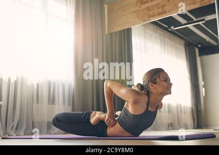 Smiling young woman practicing yoga in studio