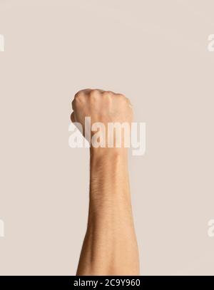 Closeup view of man raising his clenched fist up on light background Stock Photo