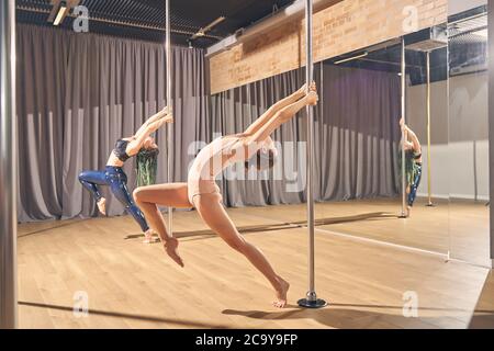 Skillful female dancers doing acrobatic tricks on pylons Stock Photo