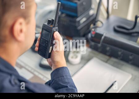 Cheerful adult male looking down while saying on the walkie talkie Stock Photo
