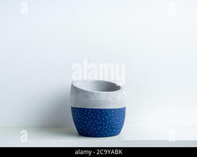 Empty modern geometric concrete planter on white shelf isolated on white wall background with copy space. Beautiful blue colour and white dot pattern Stock Photo