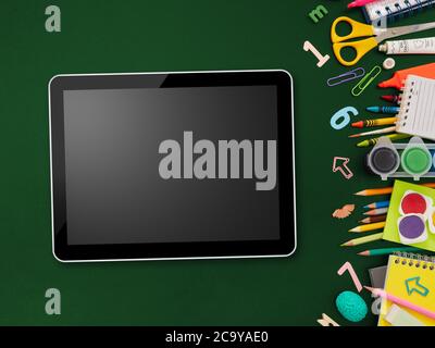 Digital tablet and school supplies on blackboard Stock Photo