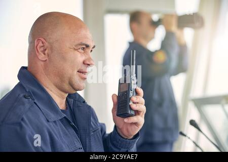 Smiling handsome worker holding walkie talkie in hand Stock Photo