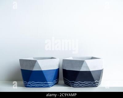 Empty modern geometric concrete planters on white shelf isolated on white wall background with copy space. Two beautiful blue and black colour painted Stock Photo