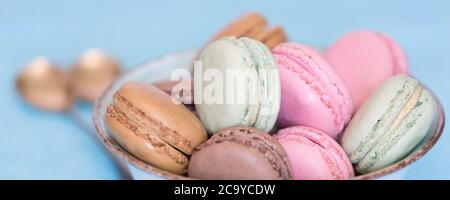 Colorful macaroons in the bowl. Sweet macarons french dessert on blue background Stock Photo