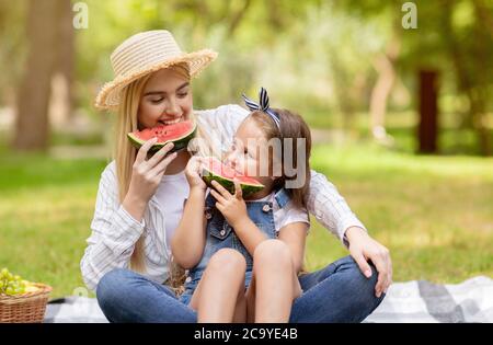 Girl And Her Mother Having Picnic Eating Watermelon In Park Stock Photo