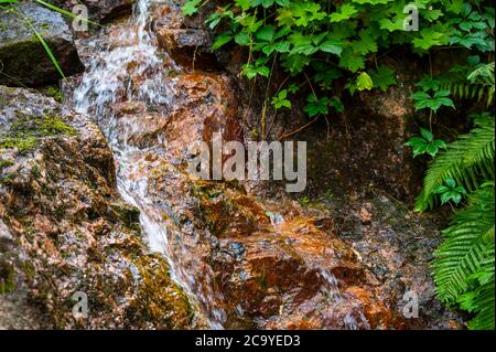 Helsinki / Finland - July 30, 2020: Closeup of a small natural stream between rocks in a public park. Stock Photo