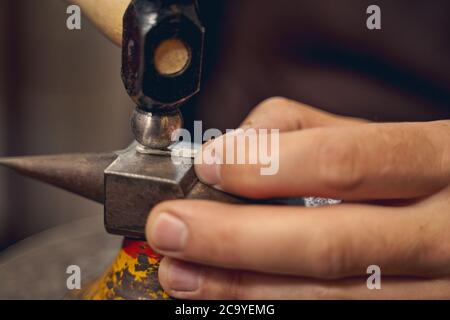 Professional Caucasian artisan using a metalsmithing tool Stock Photo