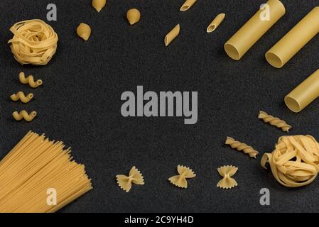Different types of pasta on black background. Dry pasta. Italian kitchen. Space for text. Stock Photo