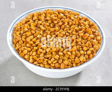 Fried and Spicy Chana Dal is a very popular Gujarati snack, white bowl on white background, pouch packing common street snack from India, selective Stock Photo