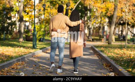 Rear view of romantic black couple walking on pathway in park Stock Photo