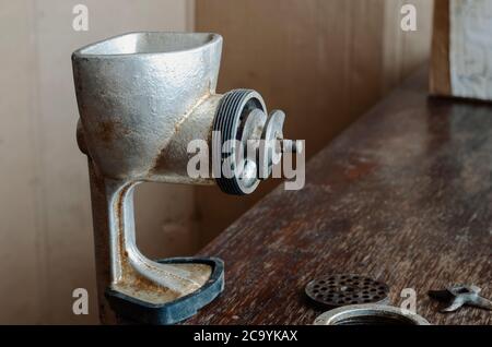 Disassembled manual vintage meat grinder on  wooden table. Hand tool for grinding various products. Antique kitchen utensils. Stock Photo