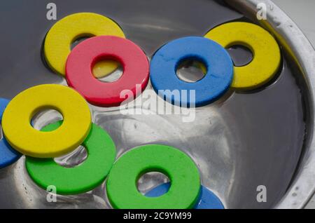 Multi-colored details of children's designer set in metal bowl with water. Cleaning children's toys from dirt and dust. Hygiene, health care. Selectiv Stock Photo