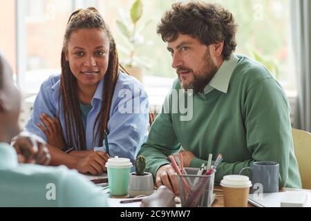 Portrait of creative bearded man brainstorming ideas while working on team project with multi-ethnic group of people, copy space Stock Photo
