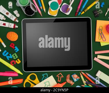 Digital tablet and school supplies on blackboard Stock Photo