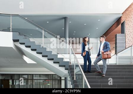 Business executives standing on stairs and discussing project details and gossips Stock Photo