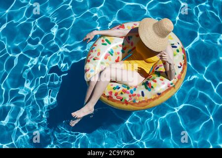 Young woman on inflatable donut ring in swimming pool, summer vacation concept Stock Photo