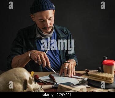 Shoemaker workshop. Shoemaker cutting leather in a workshop. Fashion designer shoes. Knife cutting. Small business and shoe manufacturing Stock Photo